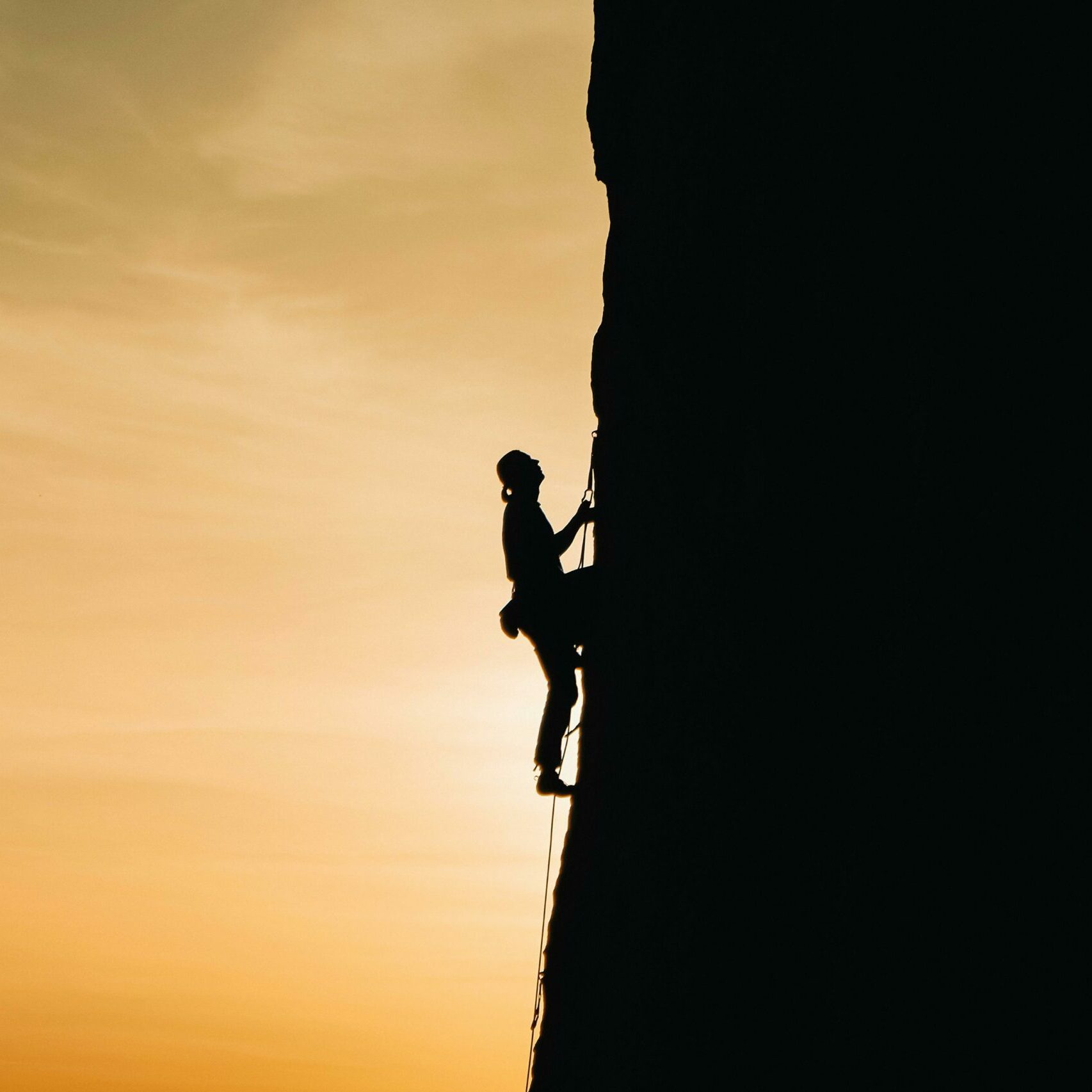 Persona arrampica su parete rocciosa con attrezzature da arrampicata, suggerendo un'esperienza avventurosa per gli amanti delle attività all'aperto.